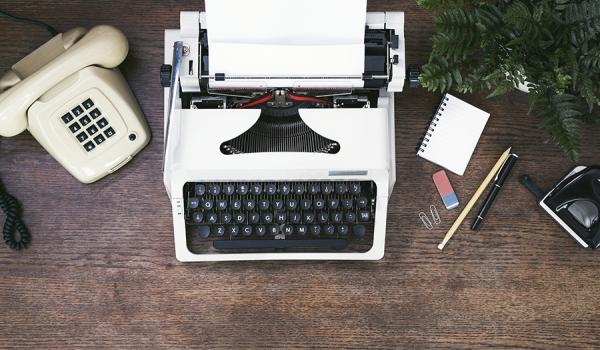 Phone, typewriter and office supplies on a wooden desk